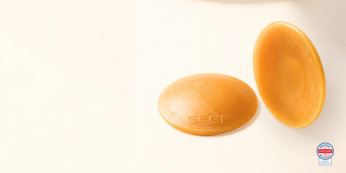 Two oval-shaped golden-yellow solid bars, likely beeswax or tallow candles, shown on a clean white background. One bar is embossed with the brand name 'GEEC'.